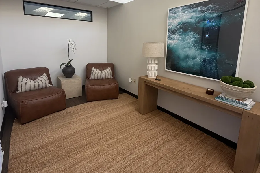 Waiting lounge with leather chairs and ocean artwork at the Bodhi Wellness Collective office in Hermosa Beach
